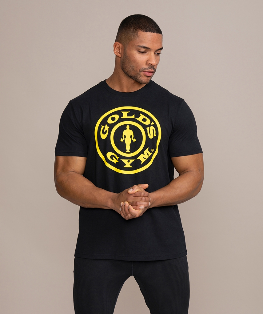 Schwarzes Sport T-Shirt von Gold’s Gym. Kurzarm Oberteil mit einem gelben Weight Plate Logo und gelber Schrift auf der Brust