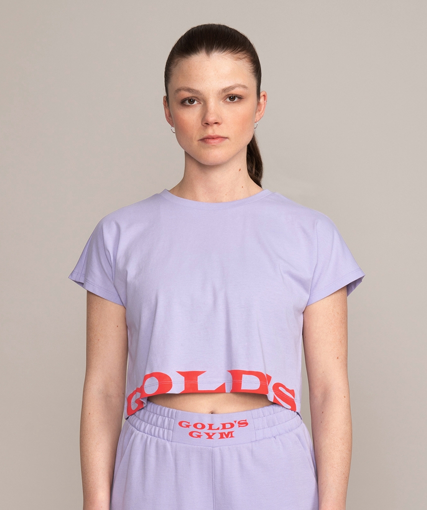 Lavendel Crop Top T-Shirt mit oragenem Gold’s Gym Logo Schriftzug auf der Vorder- & Rückseite. 